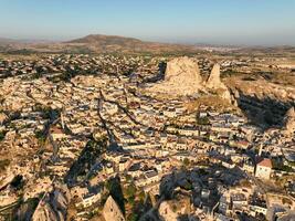 Aerial view of natural rock formations in the sunset, valley with cave houses in Cappadocia, Turkey. Natural landscape city lights at the night. photo