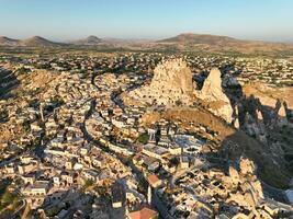 Aerial view of natural rock formations in the sunset, valley with cave houses in Cappadocia, Turkey. Natural landscape city lights at the night. photo