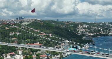Istanbul Bosphorus Bridge and City Skyline in Background with Turkish Flag at Beautiful Sunset, Aerial slide orbiting and tracking shot photo