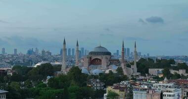 Establishing orbiting aerial drone shot of a Hagia Sophia Holy Grand Mosque with Bosphorus bridge and city skyline with a flag on the background in Fatih, Istanbul, Turkey at sunset. photo