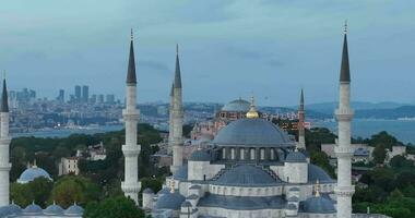 Establishing orbiting aerial drone shot of a Hagia Sophia Holy Grand Mosque with Bosphorus bridge and city skyline with a flag on the background in Fatih, Istanbul, Turkey at sunset. photo