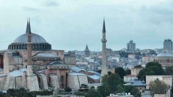 Establishing orbiting aerial drone shot of a Hagia Sophia Holy Grand Mosque with Bosphorus bridge and city skyline with a flag on the background in Fatih, Istanbul, Turkey at sunset. photo