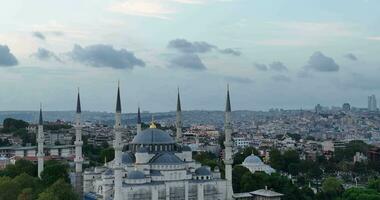 Establishing orbiting aerial drone shot of a Hagia Sophia Holy Grand Mosque with Bosphorus bridge and city skyline with a flag on the background in Fatih, Istanbul, Turkey at sunset. photo