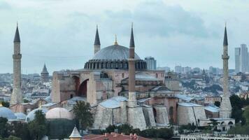 Establishing orbiting aerial drone shot of a Hagia Sophia Holy Grand Mosque with Bosphorus bridge and city skyline with a flag on the background in Fatih, Istanbul, Turkey at sunset. photo