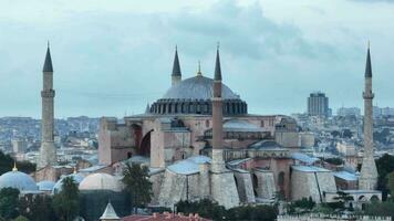 Establishing orbiting aerial drone shot of a Hagia Sophia Holy Grand Mosque with Bosphorus bridge and city skyline with a flag on the background in Fatih, Istanbul, Turkey at sunset. photo