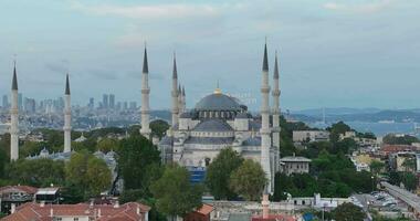 Establishing orbiting aerial drone shot of a Hagia Sophia Holy Grand Mosque with Bosphorus bridge and city skyline with a flag on the background in Fatih, Istanbul, Turkey at sunset. photo