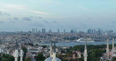 Establishing orbiting aerial drone shot of a Hagia Sophia Holy Grand Mosque with Bosphorus bridge and city skyline with a flag on the background in Fatih, Istanbul, Turkey at sunset. photo