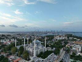 Establishing orbiting aerial drone shot of a Hagia Sophia Holy Grand Mosque with Bosphorus bridge and city skyline with a flag on the background in Fatih, Istanbul, Turkey at sunset. photo