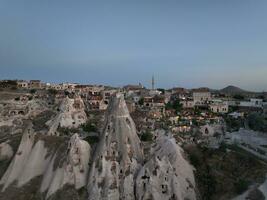 Aerial view of natural rock formations in the sunset, valley with cave houses in Cappadocia, Turkey. Natural landscape city lights at the night. photo