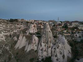 Aerial view of natural rock formations in the sunset, valley with cave houses in Cappadocia, Turkey. Natural landscape city lights at the night. photo