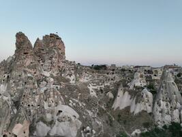 Aerial view of natural rock formations in the sunset, valley with cave houses in Cappadocia, Turkey. Natural landscape city lights at the night. photo