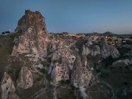 Aerial view of natural rock formations in the sunset, valley with cave houses in Cappadocia, Turkey. Natural landscape city lights at the night. photo