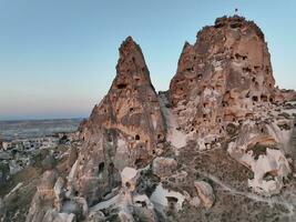 Aerial view of natural rock formations in the sunset, valley with cave houses in Cappadocia, Turkey. Natural landscape city lights at the night. photo