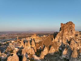 Aerial view of natural rock formations in the sunset, valley with cave houses in Cappadocia, Turkey. Natural landscape city lights at the night. photo