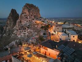 Aerial view of natural rock formations in the sunset, valley with cave houses in Cappadocia, Turkey. Natural landscape city lights at the night. photo