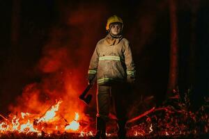 Firefighter at job. Firefighter in dangerous forest areas surrounded by strong fire. Concept of the work of the fire service photo