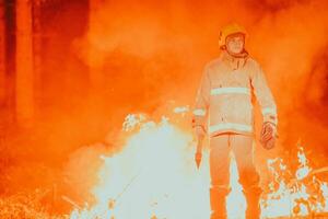 Firefighter at job. Firefighter in dangerous forest areas surrounded by strong fire. Concept of the work of the fire service photo