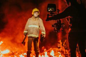 un camarógrafo con profesional equipo y estabilización para el cámara grabación el bombero mientras ejecutando trabajo en un ardiente bosque foto