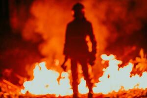 Firefighter at job. Firefighter in dangerous forest areas surrounded by strong fire. Concept of the work of the fire service photo