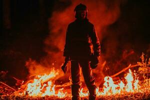 Firefighter at job. Firefighter in dangerous forest areas surrounded by strong fire. Concept of the work of the fire service photo