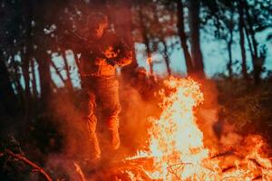 Soldier in Action at Night in the Forest Area. Night Time Military Mission jumping over fire photo