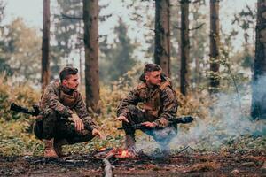 dos agotado soldados sentado por el fuego después un cansado y pesado guerra batalla foto