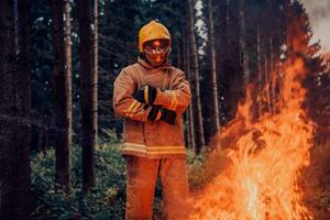 Firefighter at job. Firefighter in dangerous forest areas surrounded by strong fire. Concept of the work of the fire service photo