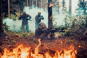 moderno guerra soldados rodeado por fuego lucha en denso y peligroso bosque areas foto