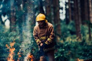 Firefighter at job. Firefighter in dangerous forest areas surrounded by strong fire. Concept of the work of the fire service photo