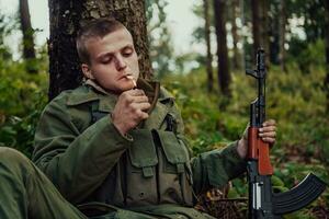 Terrorist have a break and smoke cigarette in forest during battle photo