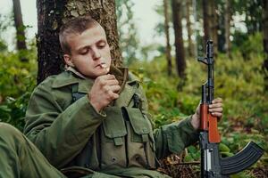 terrorista tener un descanso y fumar cigarrillo en bosque durante batalla foto