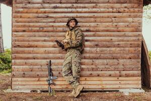 soldado utilizando tableta computadora en contra antiguo de madera pared en militar acampar a permanecer en contacto con amigos y familia foto