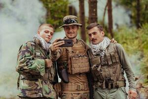 equipo de soldados y terrorista tomando selfie con teléfono inteligente en el bosque foto