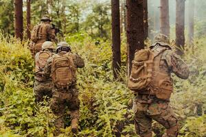 A group of modern warfare soldiers is fighting a war in dangerous remote forest areas. A group of soldiers is fighting on the enemy line with modern weapons. The concept of warfare and military conflicts photo