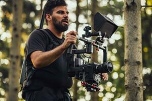 Videographer with Professional Movie Video Camera Gimbal Stabilizing Equipment Taking Action Shoot of Soldiers in Action in Forest photo