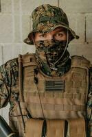 A soldier in uniform stands in front of a stone wall in full war gear preparing for battle photo