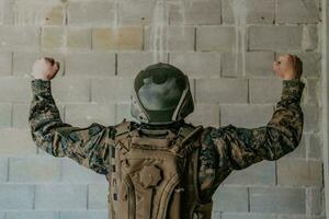 Success in the war campaign. A soldier with raised hands celebrates the successful conquest of enemy territory photo