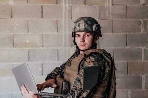 American soldier in military uniform using laptop computer for drone controlling and to stay in contact with friends and family photo