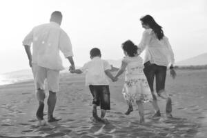 familia joven feliz divertirse en la playa al atardecer foto