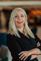 Portrait of business senior woman with crossed arms standing in modern corporation. Selective focus photo