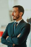 retrato de un empresario en un traje con su brazos cruzado en un moderno oficina edificio foto