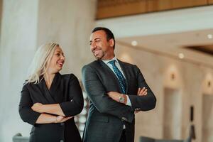 Portrait photo of businessman and businesswoman with crossed arms standing in modern corporation. Selective focus