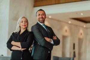 Portrait photo of businessman and businesswoman with crossed arms standing in modern corporation. Selective focus