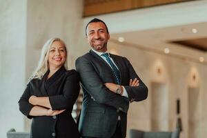 Portrait photo of businessman and businesswoman with crossed arms standing in modern corporation. Selective focus