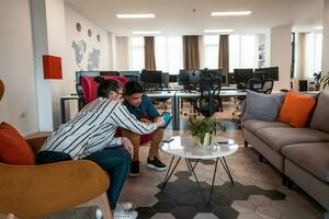 Group of casual multiethnic business people taking break from the work doing different things while enjoying free time in relaxation area at modern open plan startup office photo