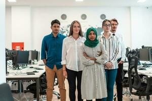 retrato de un joven equipo de negocios multiétnico emocionado de desarrolladores de software de pie y mirando la cámara en la oficina de inicio moderna foto