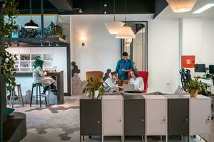 Group of casual multiethnic business people taking break from the work doing different things while enjoying free time in relaxation area at modern open plan startup office photo