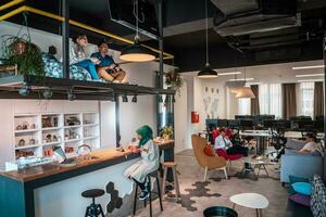 Group of casual multiethnic business people taking break from the work doing different things while enjoying free time in relaxation area at modern open plan startup office photo