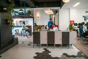 Group of casual multiethnic business people taking break from the work doing different things while enjoying free time in relaxation area at modern open plan startup office photo