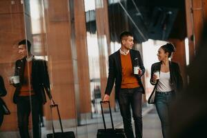 hombre de negocios y mujer de negocios hablando y sosteniendo equipaje viajando en un viaje de negocios, llevando café recién hecho en sus manos.concepto de negocio foto